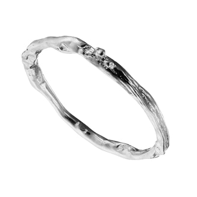 A solid white gold wedding ring with a twig wedding ring band on a white background