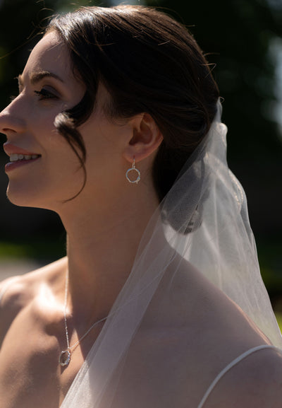 Woman wearing a veil and twig silver necklace with matching earrings.